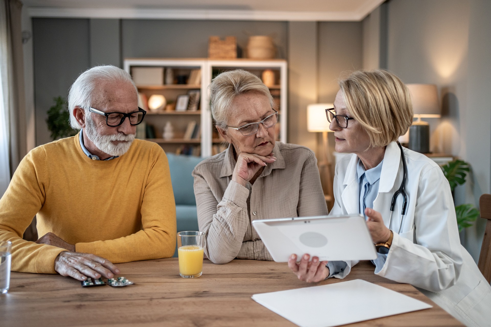 Senior couple discussing medical information with doctor on tablet