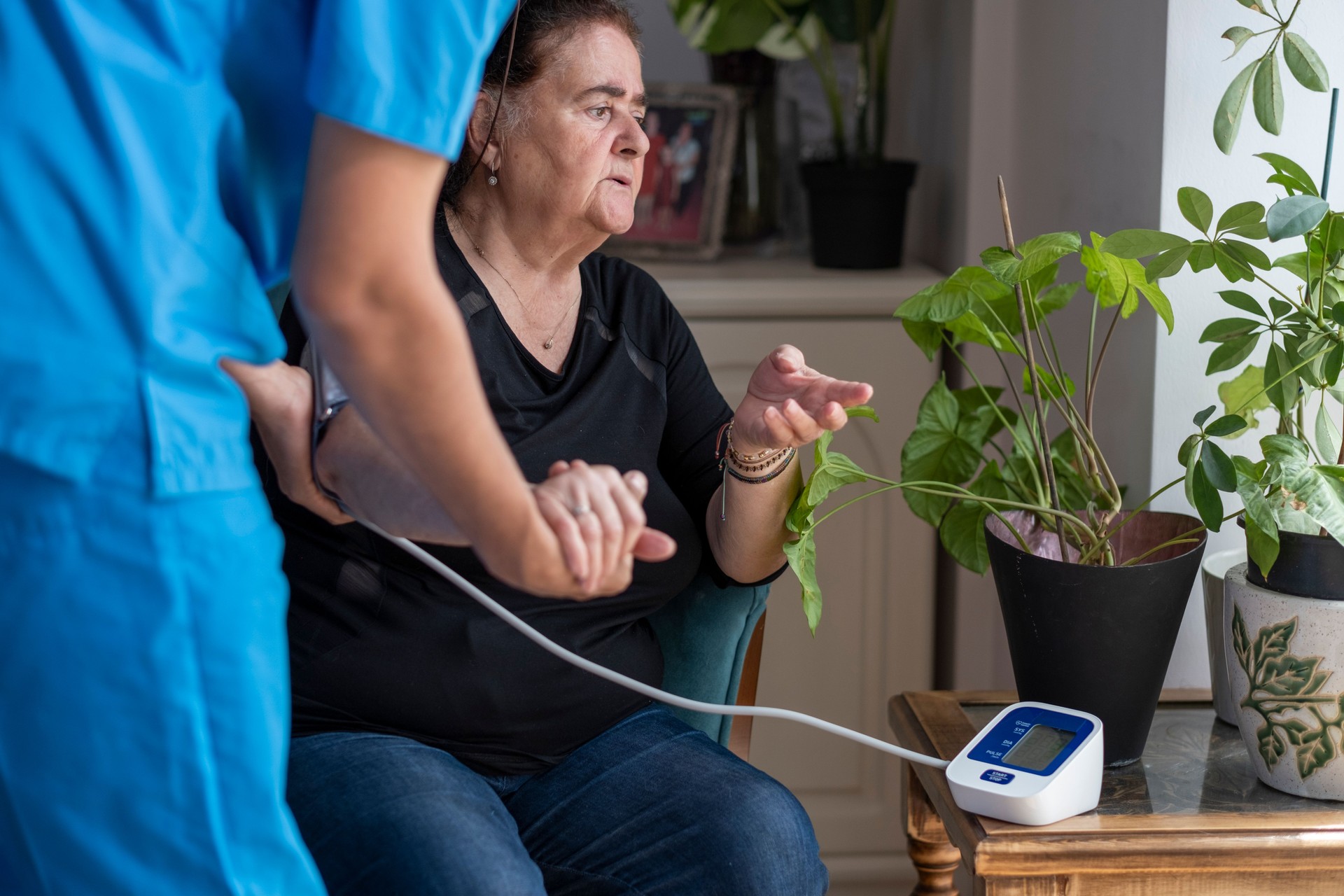 Male nurse measuring blood pressure of a senior woman at home